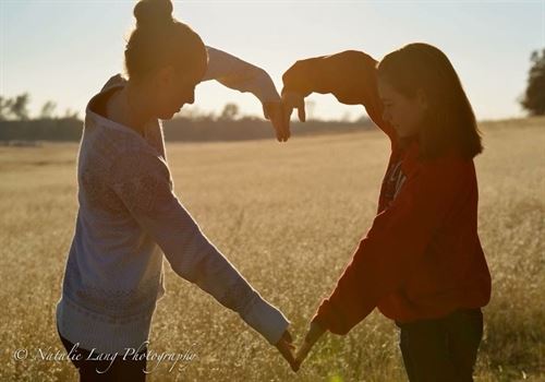 two girls making a heart with arms